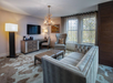 Elegant living area with sofa, work desk and chair, coffee table, and a deer antler chandelier.