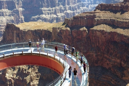 Guest on the Grand Canyon Skywalk enjoying the views of one of the Grand Canyon on a bright sunny day.