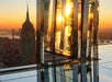 Sunset view of the Empire State Building from a high vantage point, with reflective glass panels capturing the sunlight.