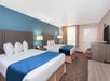 Two double beds, a chair, desk and flat-screen TV