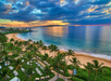 A beach with palm trees at sunset, showing loungers on the sand and a calm ocean reflecting the colorful sky.