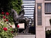 Equestrian statue near the Oregon Historical Society, with a backdrop of a modern building and blooming red roses in the foreground.