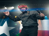 Performer on stage with red bandana, holding a microphone, and gesturing energetically. Texas flag in the background.