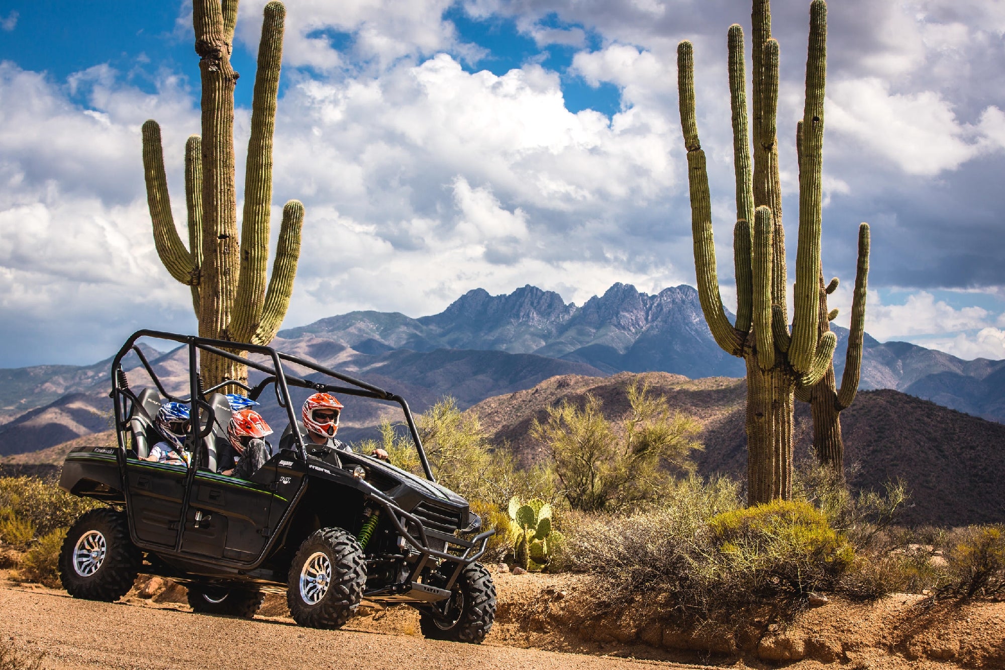 A fun-filled family adventure in a four-seater UTV, cruising through rugged desert trails surrounded by breathtaking views and iconic cacti.