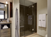 A modern bathroom with a vanity on the left and a walk in shower with dark tile and glass doors on the right.