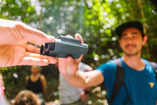 A tour guest getting handed binoculars on the Hakalau Birdwatching Tour in Kona Hawaii, USA.