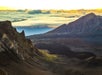 The sun rising above the distant clouds with mountains in the foreground on the Haleakala Sunrise Tour in Wailuku Hawaii, USA.