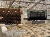 Wine tasting area with bottles on a wooden rack, a chalkboard menu displaying wine options, and empty glasses on a counter beneath a pergola roof.