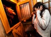 A person recoils in fear inside a wooden room as a grotesque, monstrous figure appears through an open door.