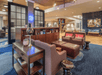 A lounge area with maroon cushioned chairs, leather ottomans, blue carpet, and lots of decorations in the lobby of the Hampton Inn and Suites.