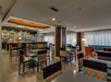Contemporary dining area with colorful chairs and tables, modern lighting, and large windows with curtains.