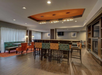 Modern hotel lobby with a communal table, stylish chairs, and a cozy seating area. Decor features earth tones and contemporary lighting. Large windows with sheer curtains illuminate the space.