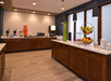 Breakfast area with counters featuring cereal dispensers, waffle makers, a microwave, a juice machine, and a fruit basket. Modern lighting and neutral decor complete the setup.