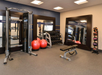 A gym with weight machines, a rack of dumbbells, large red exercise balls, a bench, medicine balls, and mirrors on the walls.