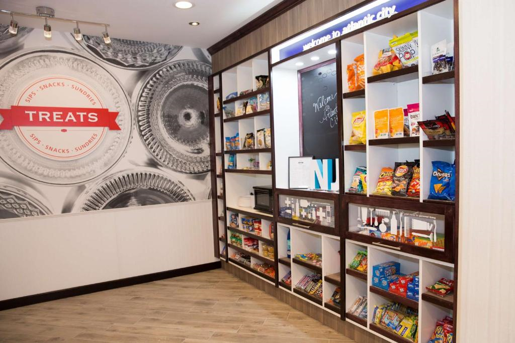Small snack shop with shelves displaying various packaged snacks. Large wall graphic on the left labeled "TREATS." Bright, clean interior with wood flooring.