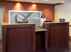 Reception desk with a smiling employee at a Hilton hotel, featuring a large photo with the word "enjoy" in the background.