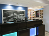 Hotel reception area with a Hilton Honors sign, POS terminals on a counter, and shelves with snacks in the background.