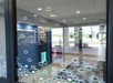 View through a glass door into a modern office lobby with a reception desk and patterned floor.