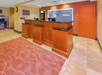 Hotel lobby with a wooden front desk, a red carpet, and a sign saying "thanks" on the wall. A vending machine is in the background.
