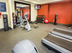 A gym with treadmills, an exercise bike, a wall-mounted TV, free weights, medicine balls, and a red exercise ball.