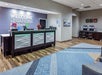 Hotel lobby with a reception desk, "Welcome to the Garden State" sign, coffee station, modern decor, and patterned blue carpet.