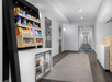 A hotel hallway with a small market stand offering snacks and drinks near two elevators, with a long corridor extending into the distance.