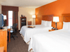 Two queen beds, work desk and a flat-screen TV inside a guest room at Hampton Inn Muskegon, MI.