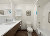 A large white bathroom with a vanity and mirror on the left, a shower and tub combo on the right, and a toilet on the far wall.