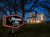 Close up of the sign for the Hampton Inn Portland Airport with the hotel in the background on a clear night.