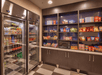 A small convenience store with refrigerated drinks, shelves of snacks, a microwave, and a checkered floor.