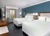 2 Queen beds and a work area inside a guest room.