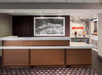 A tall brown front desk with white counter tops with a painting on the wall behind it and a treats section in the corner.