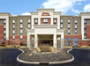 The front entrance to the Hampton Inn & Suites Columbus-Easton Area on a bright day with clouds in the sky.