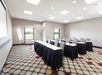 Meeting facility with long table setup, a white board and a white projector screen.