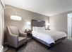 One king bed, armchair, wall mounted and floor lamps inside a non-smoking room.