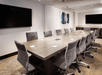 Meeting facility with a long table, executive chairs and flat-screen TVs.