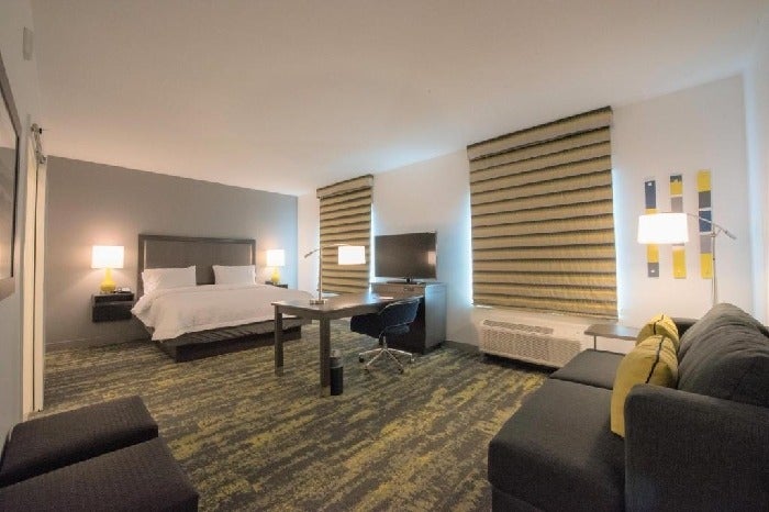 Guest room with king-sized bed, spacious seating area, and flat-screen TV.
