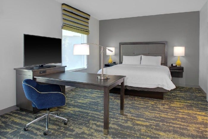 One king bed with premium beddings, flat-screen TV, and work desk in a guest room.