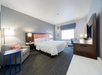 One king bed, bedside lamps, seating area, air condition, and TV in a guest room.