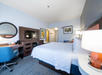 One king bed, bedside lamps, seating area, air condition, and TV in a guest room.