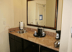 A hotel room sink with a mirror hanging over it and a coffee maker and ice bucket on the counter next to it.