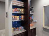 A small grocery area with shelves full of different types of chips, candy and other snacks.