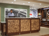 Front desk/reception area with a hotel staff behind the desk and a mini grocery nearby.