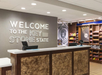 Hotel reception area with a sign reading "Welcome to the Keystone State," two check-in counters, and shelves stocked with snacks in the background.