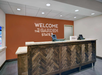 Hotel front desk with a sign that reads "Welcome to the Garden State." Two computer monitors and a sign with "Hilton" on the counter.
