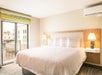One king-sized clean and fresh Hampton bed®, bedside lamps, and air condition in a guest room.