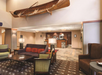 Hotel lobby with upholstered chairs, sofas, coffee tables, and a reception desk in the background. A wooden canoe is mounted on the wall above.