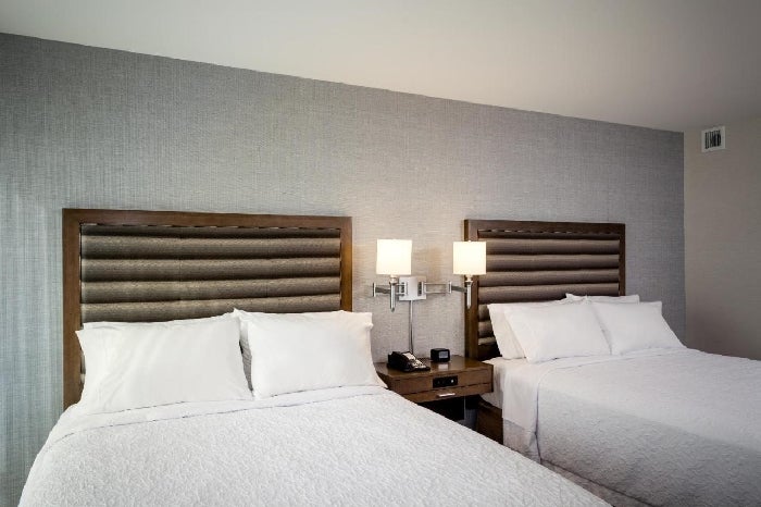 Two beds, bedside lamps, and telephone inside a guest room.