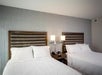 Two beds, bedside lamps, and telephone inside a guest room.
