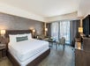 1 King bed, a sofa, and chair inside a guest room with floor-to-ceiling windows.